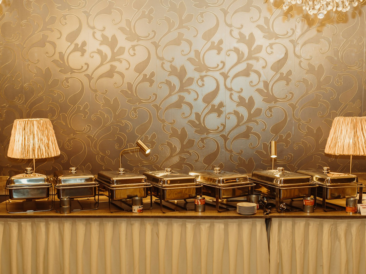 A row of covered chafing dishes laid out along a banquet table before service