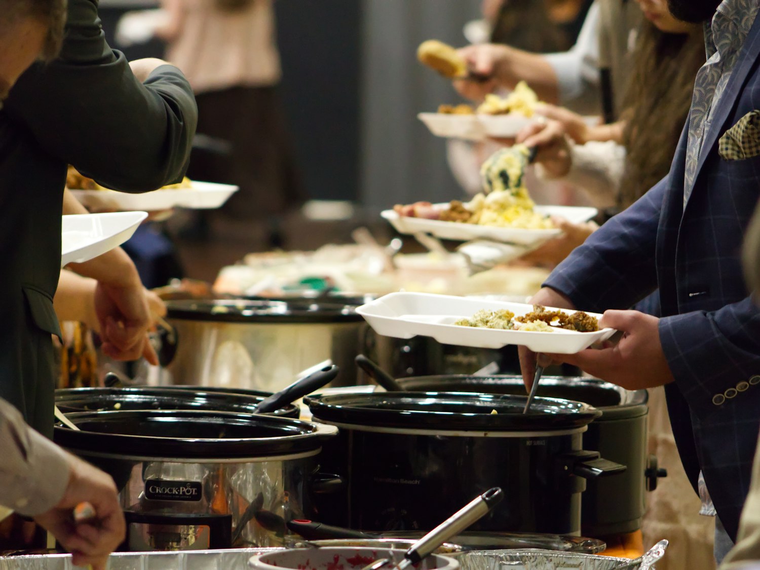 Guests filling their plates along the hot line at a catered function