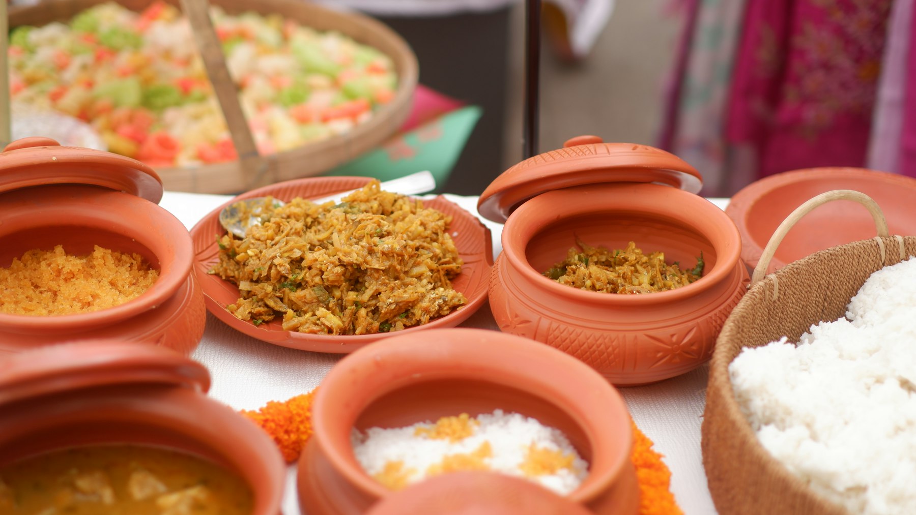 Clay handis of biryani and salad set out on a serving table